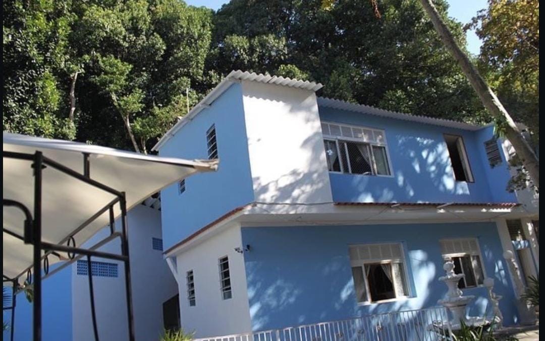 Fachada azul da casa cercada por árvores altas