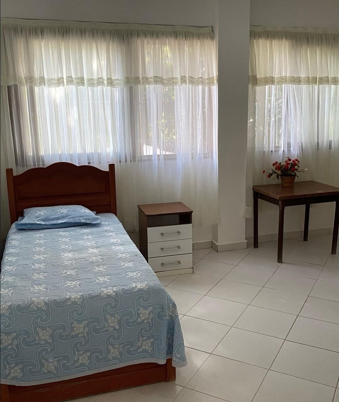Quarto amplo com cortinas claras e luz natural